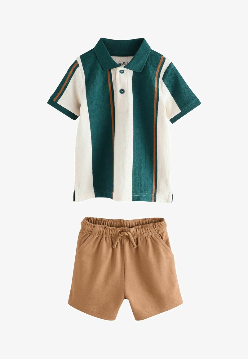 Polo à manches courtes avec rayures verticales vertes, blanches et brunes, associé à un short beige à taille élastique avec cordon de serrage.