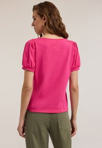 Tricou roz strălucitor cu mâneci scurte tip puff și decolteu rotund, realizat dintr-un material moale. Vederea din spate prezintă un design simplu, fără cusături.