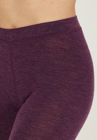Lila leggings med en mjuk textur, bred midja och elastiskt tyg, utformade för komfort och rörelsefrihet.