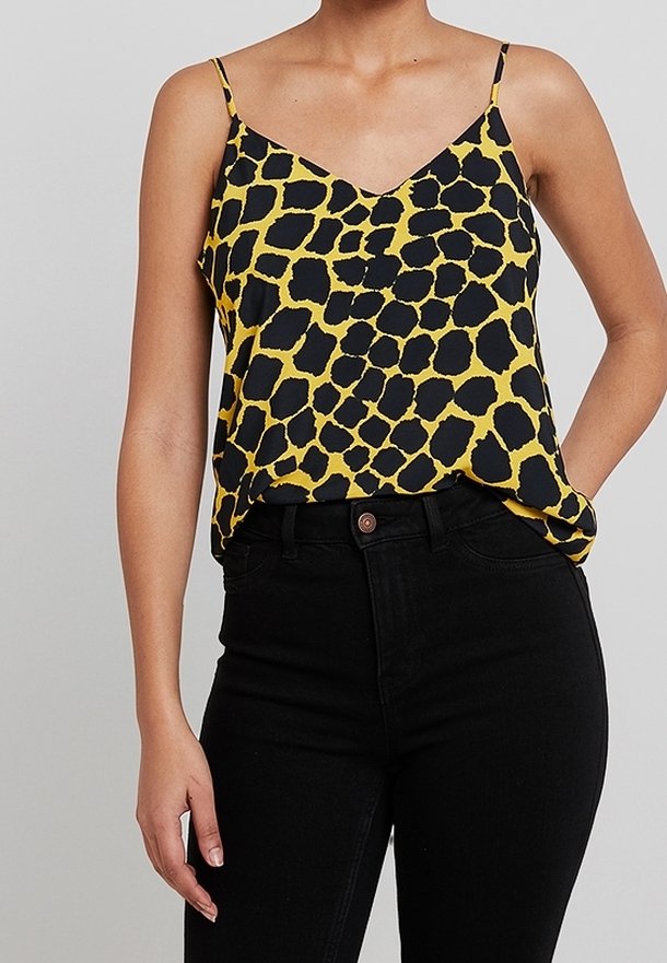 Top giallo con stampa leopardata nera, dotato di spalline regolabili e scollatura a V, abbinato a jeans neri a vita alta.