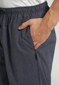 Blauwe gestreepte shorts met een elastische tailleband, voorzien van een zijzak met ritssluiting. De stof heeft een gladde, lichte textuur.