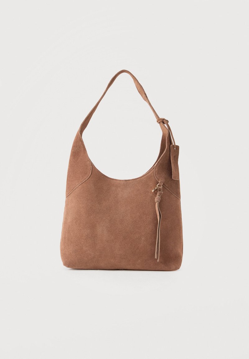 Sac hobo en daim marron avec une seule anse d'épaule et un pompon décoratif sur un fond uni.