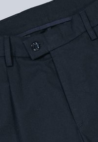 Black cotton trousers feature a button closure, belt loops, and front pleats. Smooth texture with subtle stitching details.