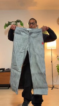 Sive kavbojke iz jeansa s krojem z ravnimi hlačnicami, pet žepov, zapiranjem na kovinski gumb in majhno rdečo etiketo na zadnjem žepu.