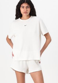 White ribbed knit t-shirt with short sleeves and round neckline, paired with matching ribbed shorts. Features small black Nike logo on chest.