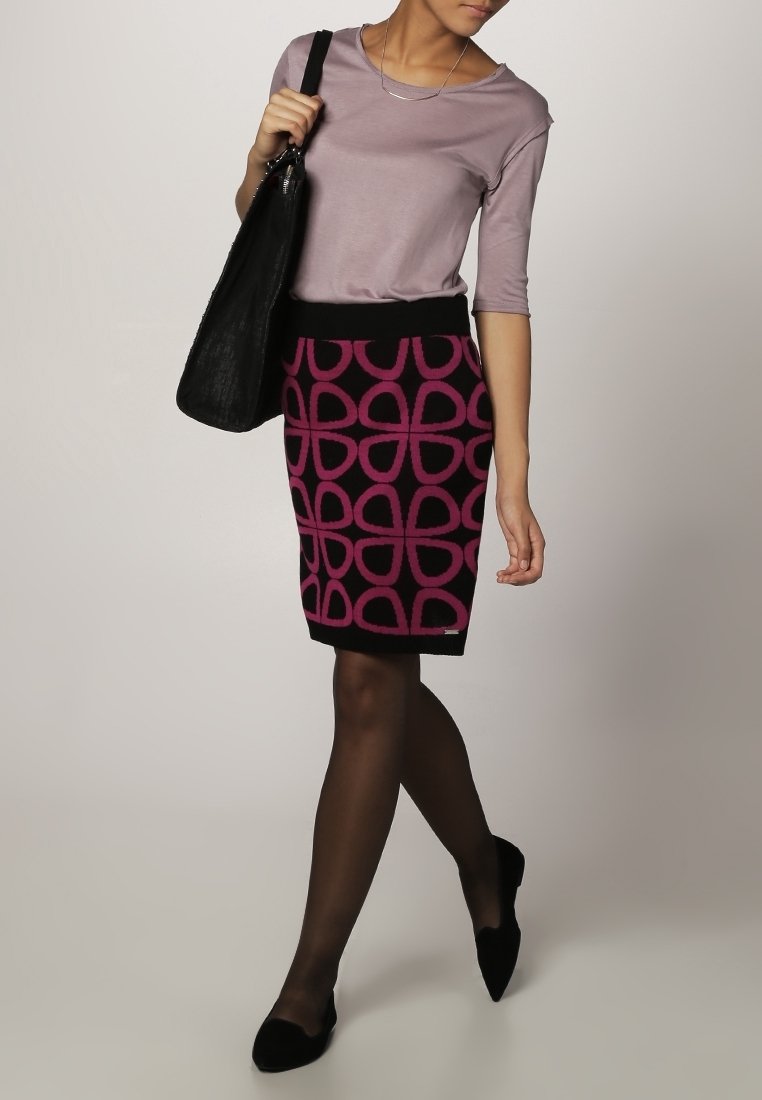 Tajt svart kjol med rosa mönster; kombinerad med en ljuslila topp och svart handväska; genomskinliga svarta strumpbyxor och svarta ballerinas.