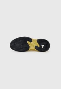 Semelle de sneaker noire avec un motif en chevrons texturé et un accent doré central. Présente un design élégant et des transitions de matériaux lisses.