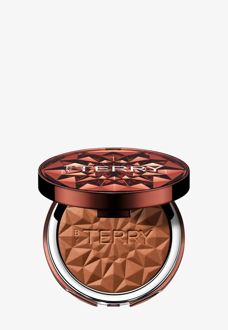 Compatto di bronzer con un coperchio in rame sfaccettato, base argentata e logo "BY TERRY" in rilievo; la polvere interna è di un marrone caldo e texturizzato.