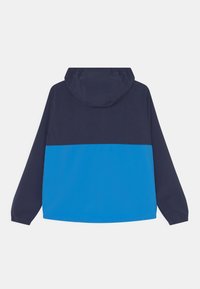Chaqueta con capucha que presenta un diseño de colores divididos: azul marino en la parte superior y azul brillante en la parte inferior. Fabricada con un tejido ligero y texturizado.