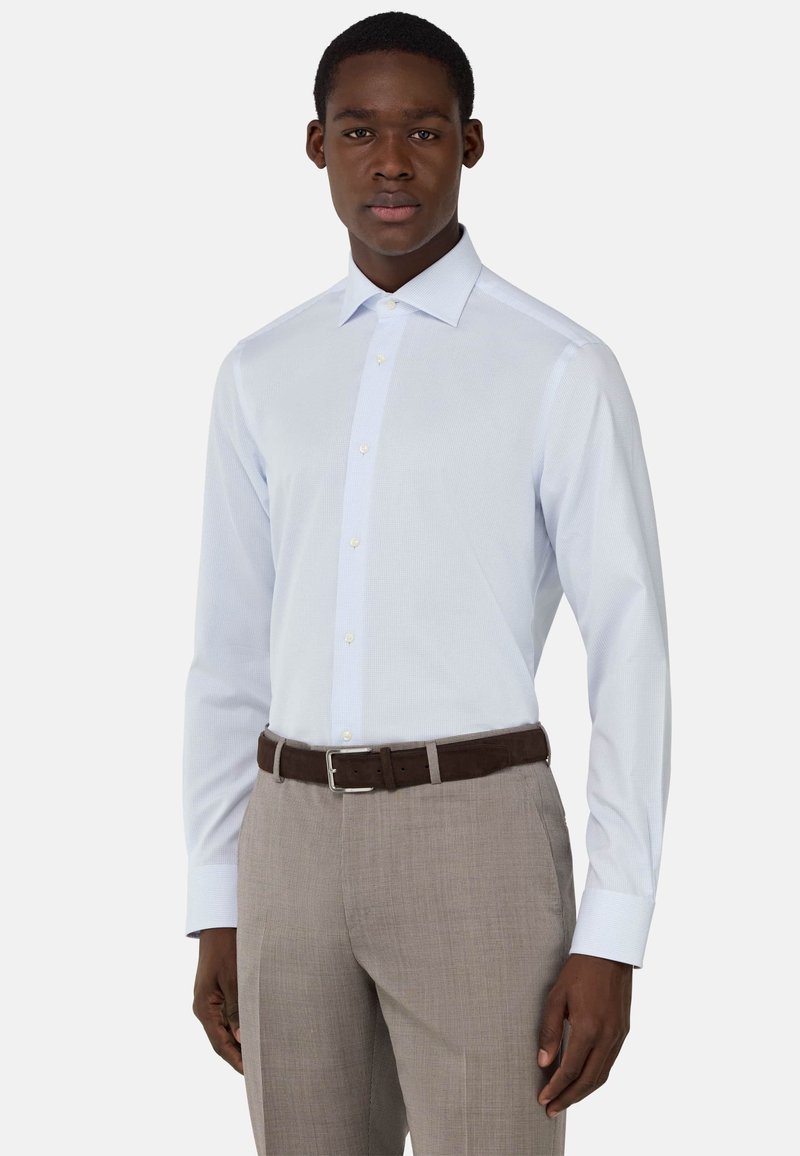 Camicia da uomo azzurro chiaro a maniche lunghe con una leggera texture e colletto classico, abbinata a pantaloni a quadretti marrone chiaro e una cintura marrone.