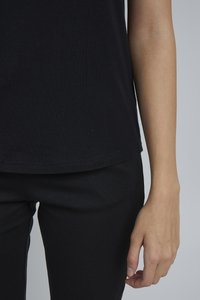 Schwarzes, körperbetontes T-Shirt mit glatter Textur, rundem Ausschnitt und kurzen Ärmeln, kombiniert mit schwarzen, schmalen Hosen. Saum sauber verarbeitet.