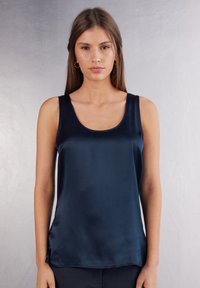 Marineblauwe satijnen tanktop met een ronde halslijn, mouwloos ontwerp en een zachte textuur. Heeft een gladde afwerking en een lichte drape aan de onderrand.