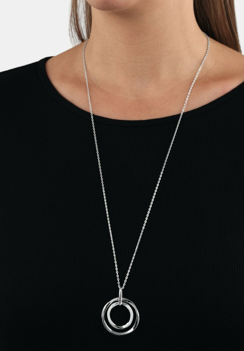 Collar de plata con un colgante de tres anillos interconectados de diferentes anchos, suspendido en una delgada cadena de plata. Los anillos tienen un acabado suave.