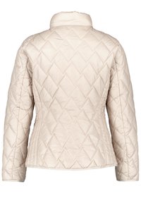 Beige quiltet jakke med opretstående krave, der har et diamantmønster og lange ærmer, lavet af letvægts og glat materiale.