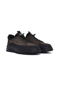 Baskets en suède olive foncé et en caoutchouc noir avec une semelle texturée, des lacets ronds et une languette au talon pour un enfilage facile.