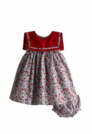 Kisgyermek ruha piros vállrésszel és fehér szoknyával, amely piros és zöld virágmintával díszített, azonos mintájú virágos bugyival párosítva.