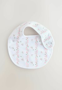 Fehér előke rózsaszín virágmintával, függőleges vonalakkal, puha anyagból, lekerekített formával és gombos záródással az állítható pánton.