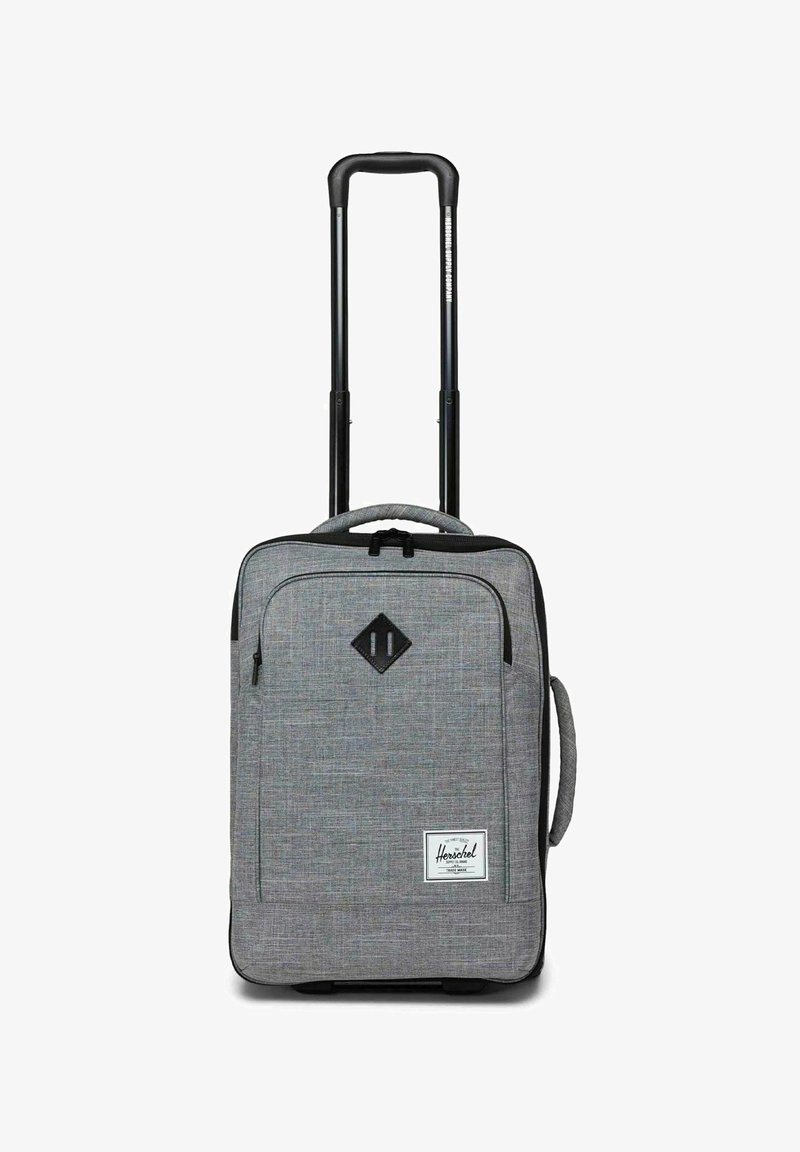 Valise cabine souple grise avec poignée rétractable noire, poche zippée sur le devant, poignée latérale et étiquette de marque Herschel à l'avant.