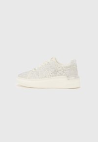 Baskets blanches avec un dessus en maille texturée décoré de clous argentés, présentant une semelle blanche rembourrée et un subtil accent métallique au niveau du talon.