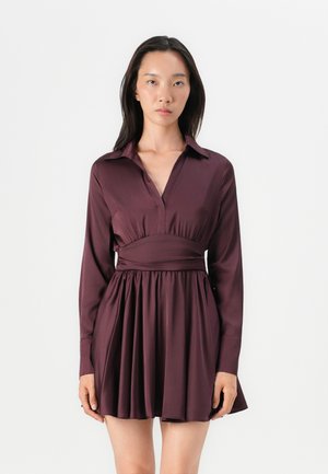 Vestido burdeos con mangas largas, cuello con solapa, cintura ceñida y falda acampanada. Tejido suave con una textura ligeramente brillante.