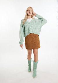 Mintgrön stickad cardigan med v-ringning och knappar, matchad med en brun mocka mini kjol och mintgröna cowboystövlar med perforeringar.