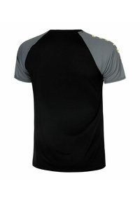 Camiseta deportiva negra con mangas cortas tipo raglán en un patrón de cuadrícula gris y detalles amarillos en los hombros. Textura suave.
