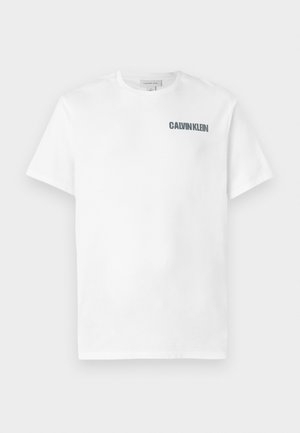 Hvid bomulds T-shirt med rund hals og korte ærmer. Har "CALVIN KLEIN" logo i mørkegrå på venstre brystområde. Glat tekstur.