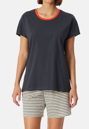 Marinblå T-shirt med röd rundhals, i kombination med krämfärgade randiga shorts. T-shirten har korta ärmar och en avkopplad passform. Mjuk bomullstyg.