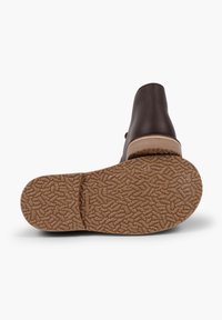 Scarpa di pelle marrone con suola in gomma texturizzata, dotata di punta rotonda e tacco basso a strati. Accentuata con un bordo in contrasto.