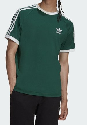 Grön kortärmad t-shirt med vita detaljer och tre vita ränder på axlarna. Har en vit Adidas-logga på bröstet.