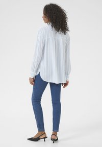 Ribakiri triibuga helesinis ja valges, pikkade varrukatega, selja voldiga detail, kombineeritud siniste kitsaste teksade ja mustade kontsadega slingback'idega.