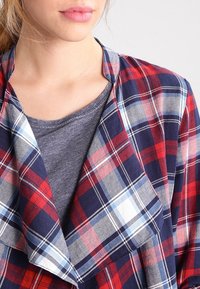 Rutig skjorta i röd, marinblå och vit med mjuk textur; lagerdesign med en grå skjorta under.