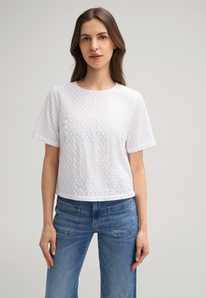 Witte katoenen t-shirt met een gestructureerd patroon, korte mouwen en een ronde hals. Gecombineerd met blauwe jeans voor een casual look.