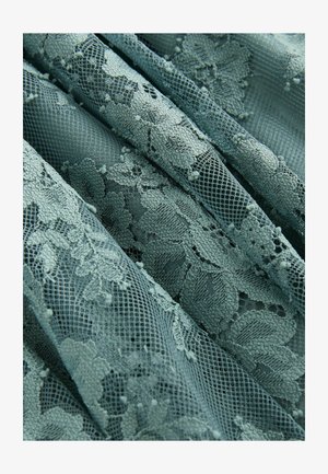 Mežģīņu audums maigi zilā krāsā ar ziedu rakstiem, kas satur teksturētus akcentus un tīklu, radot slāņainu un sarežģītu izskatu.