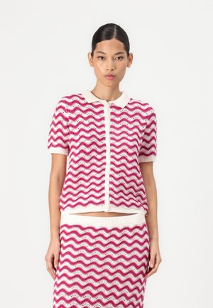 T-shirt en tricot à manches courtes avec un motif en vagues rose et blanc, doté d'un col et d'une fermeture à boutons. Accompagné d'une jupe assortie.