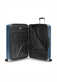 Maleta rígida azul abierta para mostrar un interior negro con patrones, con compartimentos con cremallera y cuatro ruedas giratorias, visible el asa extensible.