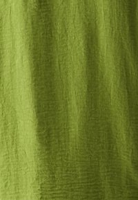 Textured fabric in a vibrant green color, featuring a soft, crinkled appearance and a lightweight material suitable for clothing or decor.