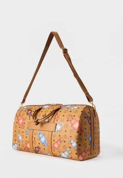 Sac de voyage en cuir fauve avec bandoulière réglable, décoré de motifs multicolores de lapins robots cartoon et de logos MCM.