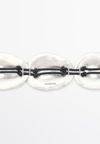 Collana dichiarativa in metallo argento con anelli ovali caratterizzati da una finitura lucida, intervallati da cordini elasticizzati neri.