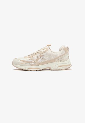 Scarpa da ginnastica atletica beige e bianca con tomaia in mesh e materiale sintetico, design con lacci, suola imbottita e linguetta di tiraggio sul tallone, vista laterale.