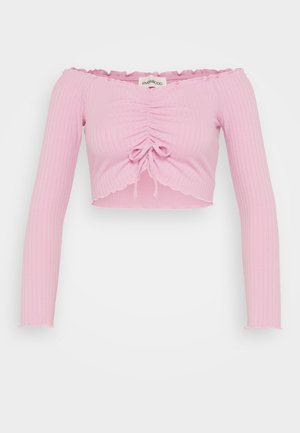 Top corto rosa de canalé, sin hombros y con mangas largas, que presenta un detalle de cordón en la parte delantera y bordes del dobladillo en forma de ondas.