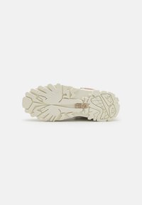 Witte sneaker zool met een robuust, gestructureerd patroon. Bevat opvallende groeven en een logo in een lichtroze kleur nabij de hiel.