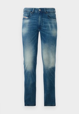 Jeans slim-fit desbotados em azul, com design de cinco pockets e fecho de botão, exibidos contra um fundo branco liso.