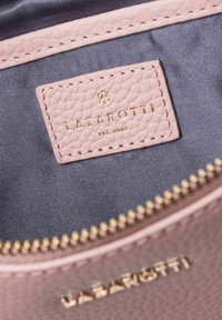 Hellrosa Lederinterieur mit einem silbernen Reißverschluss. Enthält ein Markenzeichen mit der Aufschrift "LAZAROTTI EST. 2007" in Gold. Weiche Textur mit sichtbaren Nähten.