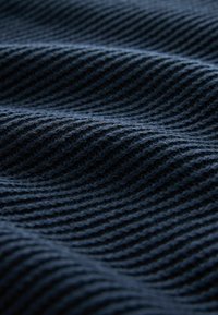 Ciemnoniebieska tkanina o fakturze z prążkowanym wzorem, charakteryzująca się miękkimi, falującymi falami oraz gładkim wykończeniem.