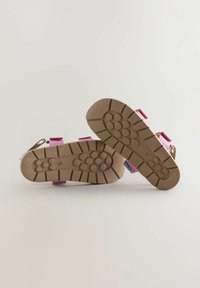 Sandali rosa e viola con una suola in gomma marrone texturizzata, dotati di cinghie regolabili e dettagli metallici per la chiusura.