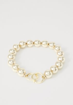 Gold beaded bracelet featuring round, shiny beads with a smooth texture, and a double-loop clasp for secure closure.