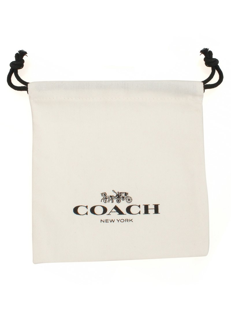 Pochette en coton à cordon de serrage crème avec un logo noir. Elle présente une texture lisse et des cordons noirs en haut pour la fermeture.