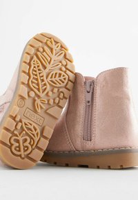Rosa Wildleder-Stiefeletten mit seitlichem Reißverschluss, strukturiertem Gummisohle mit Blattmustern und glatter Oberfläche im oberen Bereich.