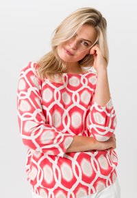 Roze en witte gebreide trui met een losse pasvorm, voorzien van een geometrisch ontwerp en driekwart mouwen, gemaakt van zacht breimateriaal.
